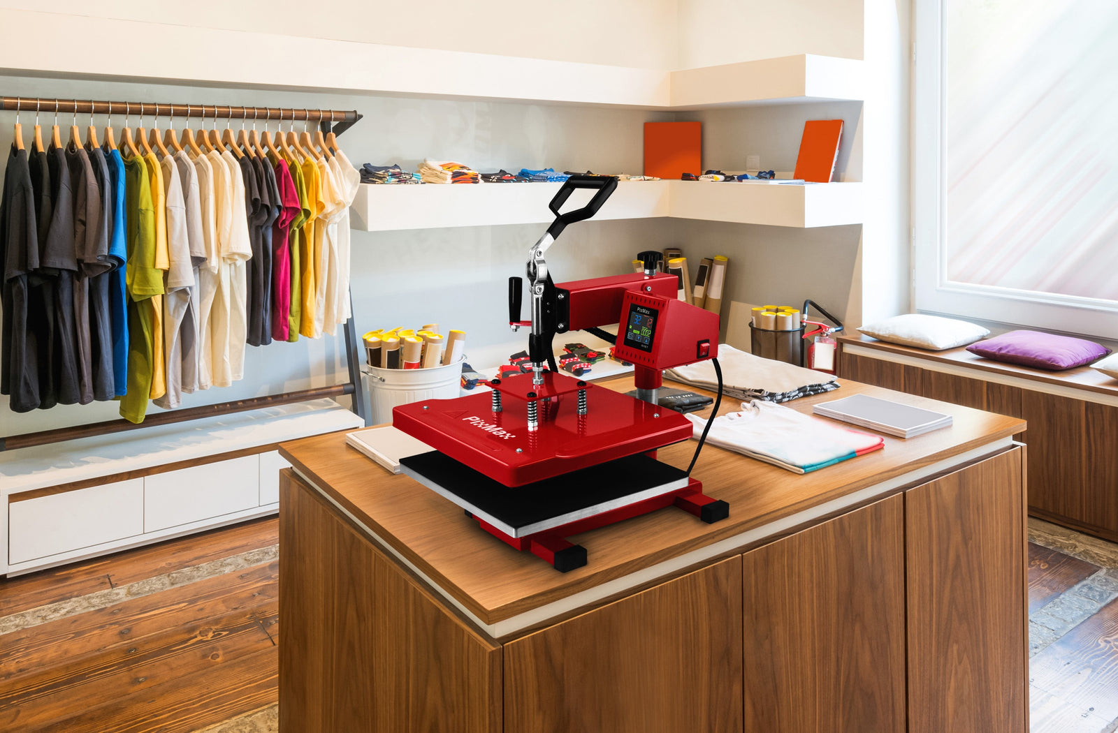 A vibrant red heat press machine on a wooden table, surrounded by colorful t-shirts and crafting supplies in a bright studio setting