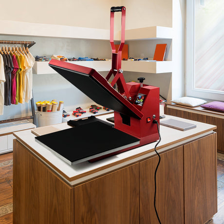 Red heat press machine on a wooden table, featuring a large black pressing surface, colorful control buttons, and a modern design in a bright room