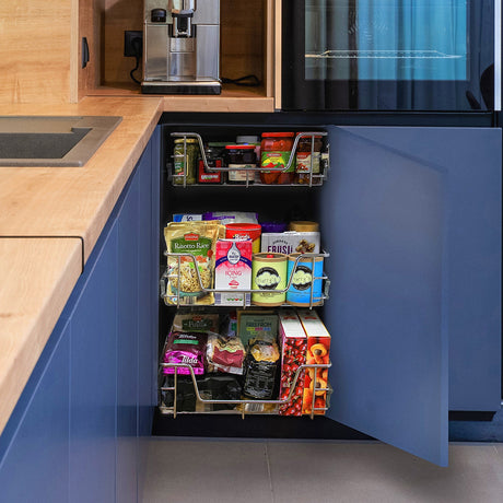 Organized kitchen cabinet featuring metal pull-out shelves filled with various food items, including spices, sauces, and snacks