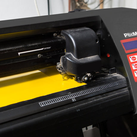 Vinyl cutting machine with a black exterior and bright yellow vinyl sheet, showcasing precision cutting tools and controls